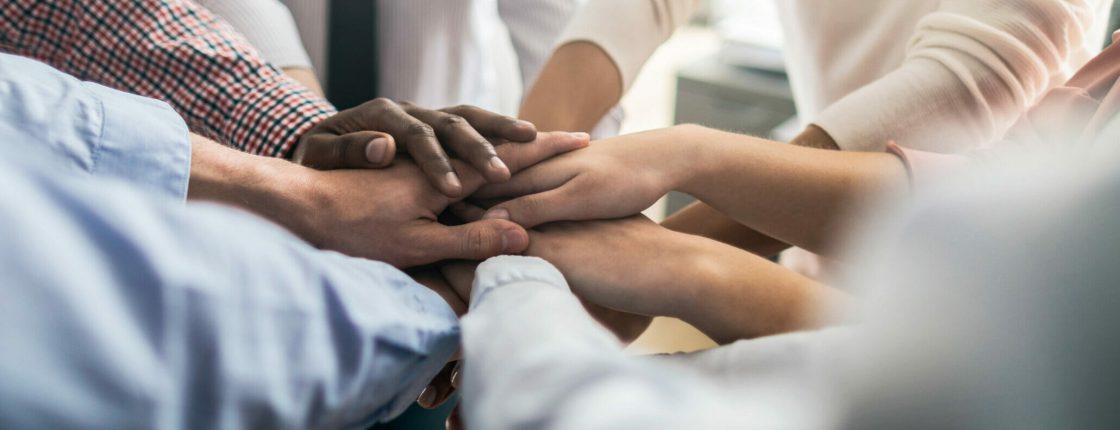 Close up view of young business people putting their hands together. Stack of hands. Unity and teamwork concept.